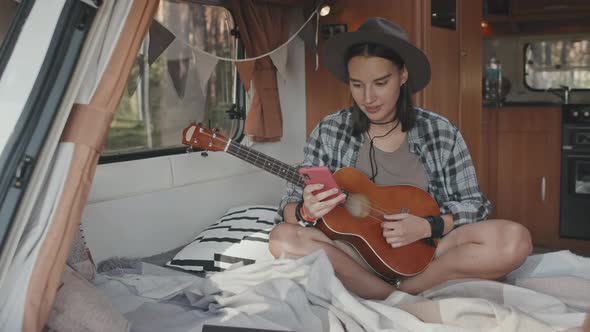 Woman with Ukulele Using Phone in Camper