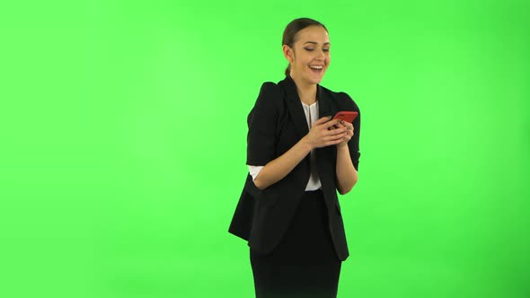 Young Smiling Woman Texting on Her Phone and Rejoice. Green Screen