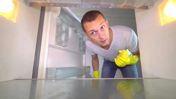 the man opens the refrigerator, sniffing and plugging his nose