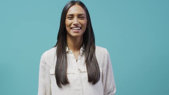 Video of happy biracial woman looking at camera on blue background