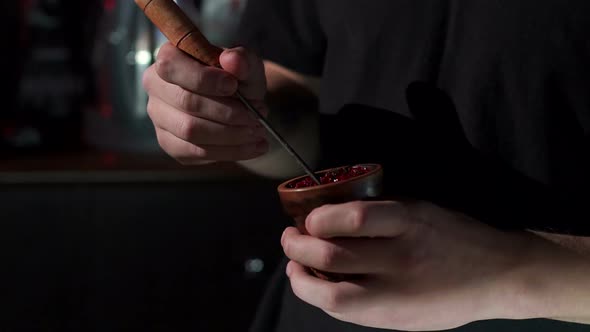 Close-up of a Man Preparing Fruit Tobacco in a Bowl for a Hookah in a Bar