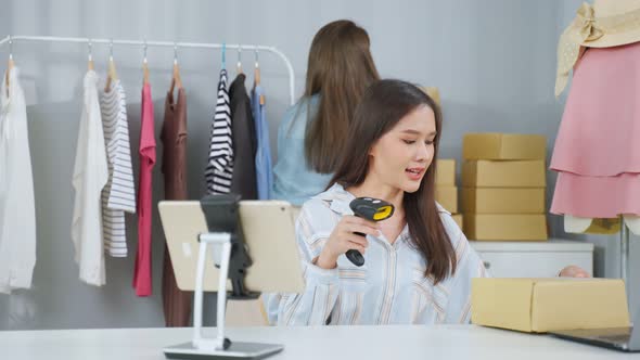 Asian two beautiful woman packing clothes order into box for customer.