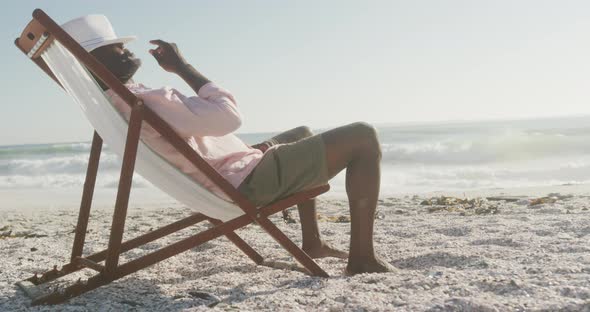 Senior african american man lying on sunbed on sunny beach