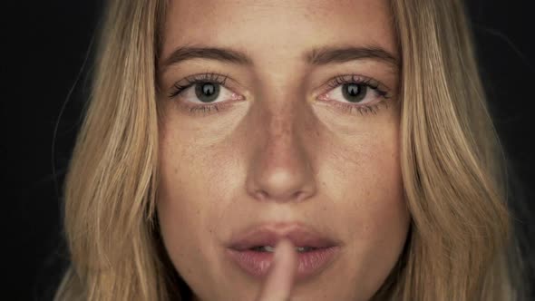 Woman holding finger to lips, close-up