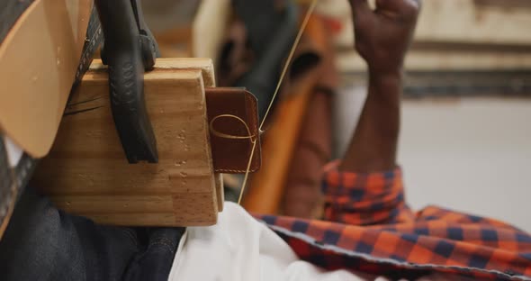 Hands of african american craftsman using tools, preparing wallet in leather workshop