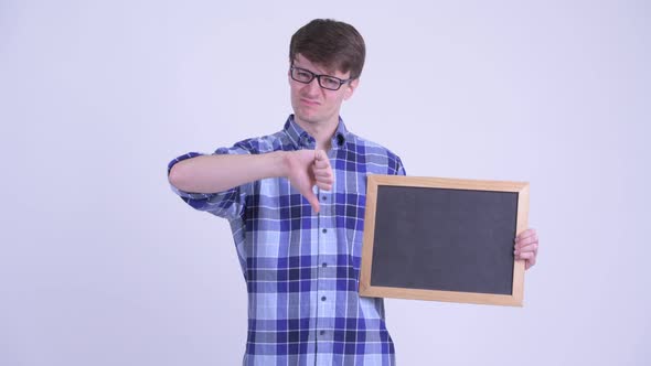 Stressed Young Hipster Man Holding Blackboard and Giving Thumbs Down