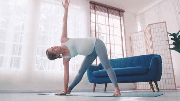 Asian pregnant woman doing yoga exercise at home.