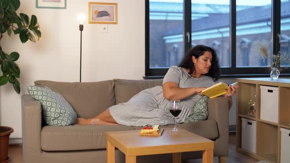 Woman Reading Book and Drinking Red Wine at Home