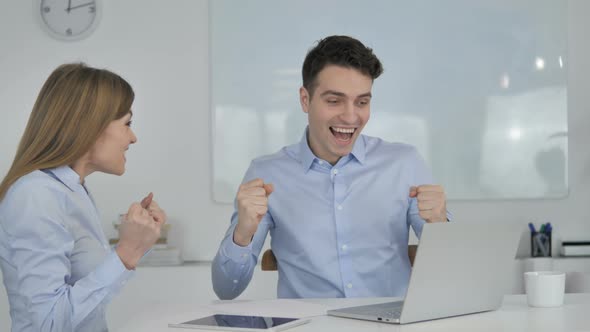 Business People Celebrating Success While Working on Laptop