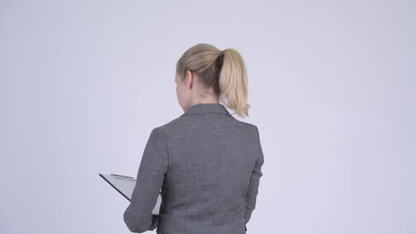 Rear View of Young Blonde Businesswoman Directing and Pointing Finger