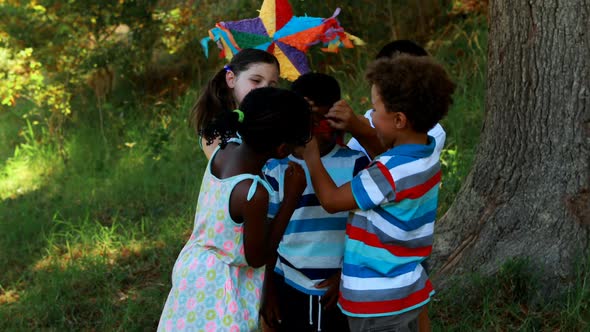 Group of kids tying blindfold on their friends eyes in park