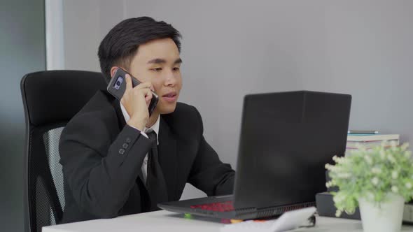 happy  young business man talking on mobile phone and using laptop