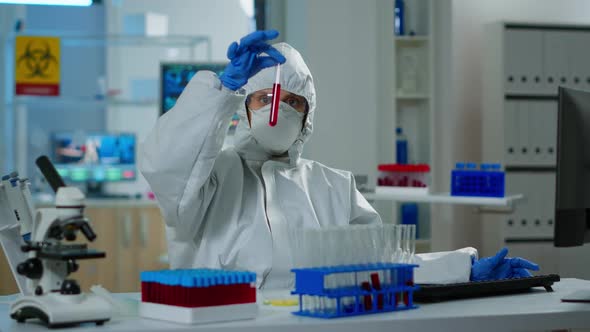 Researcher in Coverall Holding Test Tubes with Blood Sample