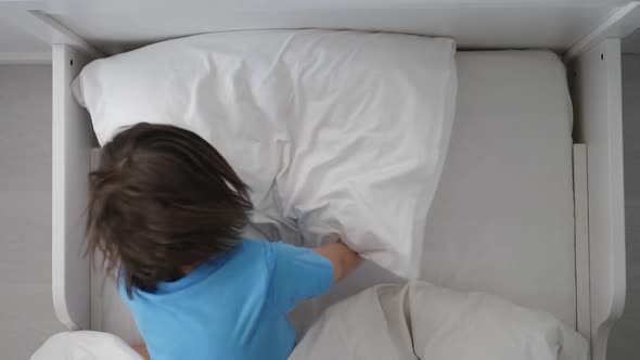 Boy Child in a Blue Tshirt Lies on a White Bed