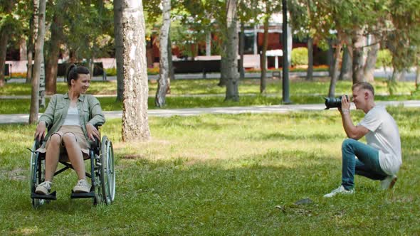 Smiling Woman in a Wheelchair and Her Friend Spending Time at the Summer Park and the Man Taking a