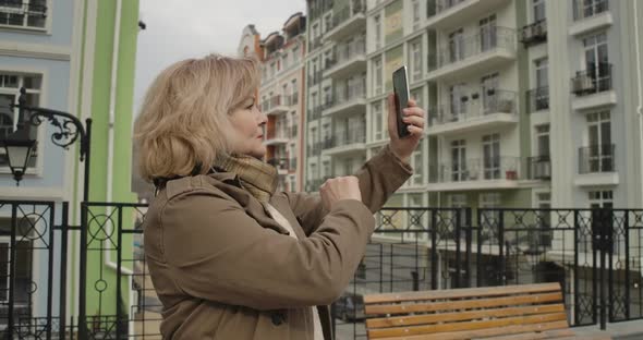 Confident Mature Caucasian Woman Taking Photos on City Street. Beautiful Senior Female Retiree