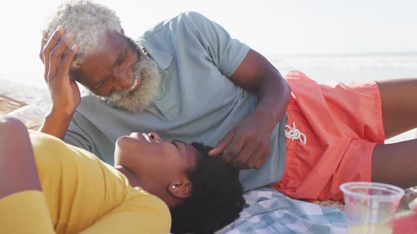 Happy african american couple having picnic on sunny beach