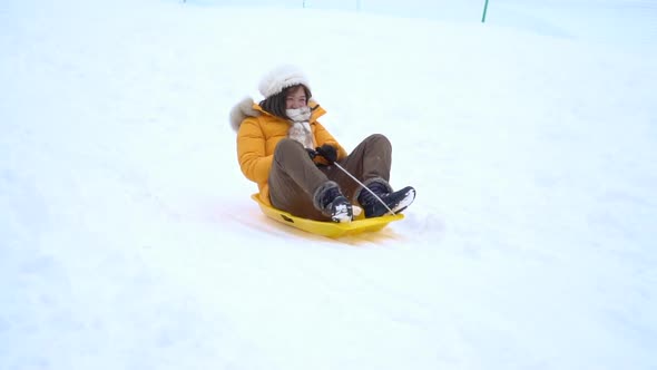 Asian Woman Playing Sled Under Snow Fall
