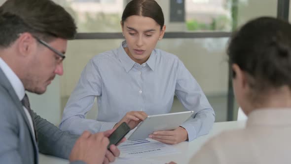 Male and Female Businessperson using Tablet and Smartphone during Discussion