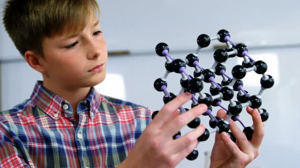 Schoolboy experimenting molecule model in laboratory at school