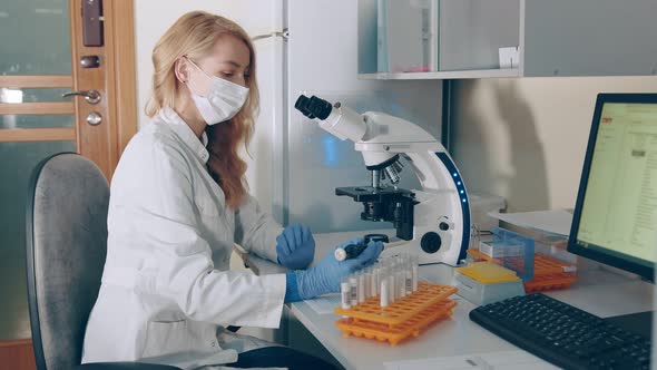 Microbiologist Works with a Microscope in a Laboratory and Research Center. A Woman of Caucasian