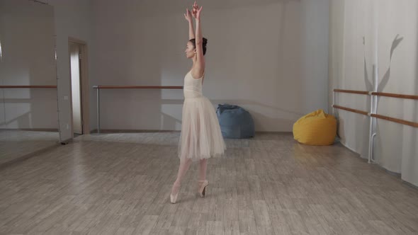 Charming Ballerina in the Dance Hall in Front of the Mirror in a Beautiful Dress Doing Pirouettes