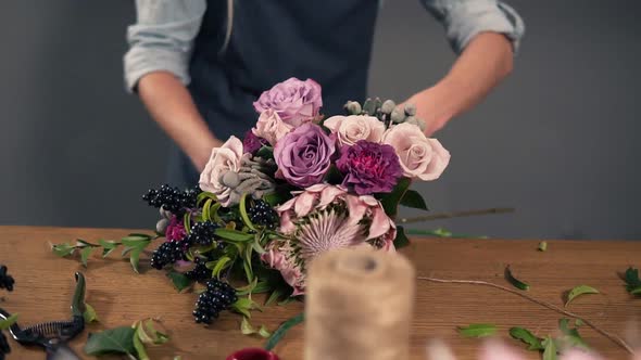 Portrait of a Young Flower Shop Assistant Tying a Bunch of Flowers Lying on Her Table with the