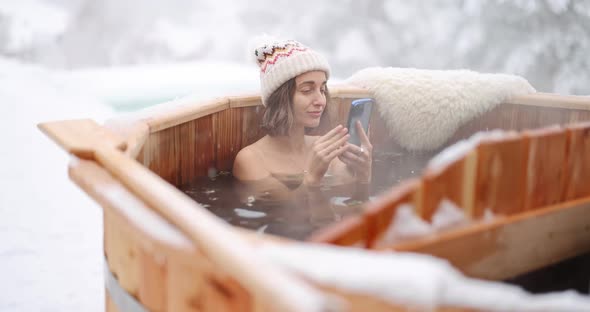 Woman Relaxing in Hot Bath at Snowy Mountains