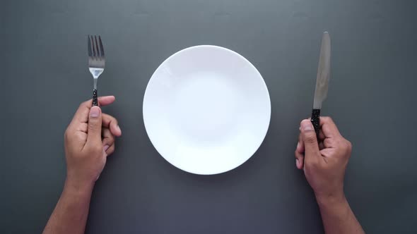 Men Holding Cutlery with Empty Plate on Black Background