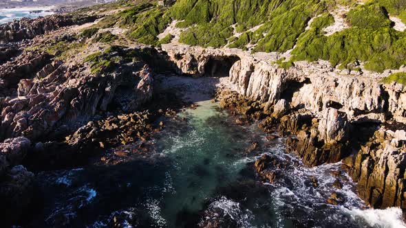 Aerial - Coastal caves of De Kelders (South Africa), drone flying backwards and ascending revealing