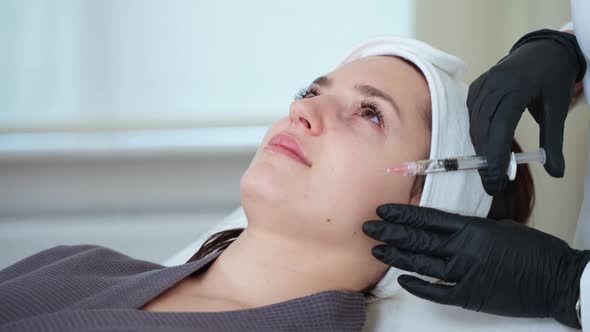 Cosmetologist is Using Injectable Filler for Rejuvenating Face Skin of Female Client