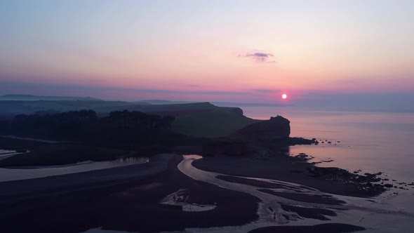 Aerial drone flying over estuary of freshwater river meeting salt water ocean, Devon England