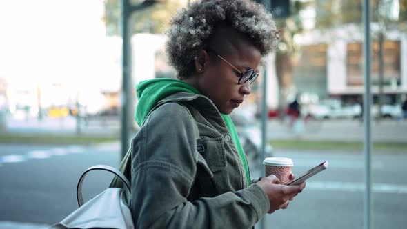 Serious adult African woman wearing casual clothes looking at phone