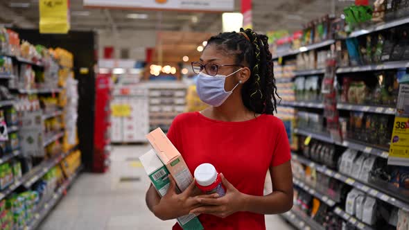 Latin young woman wearing a face mask shopping in supermarket