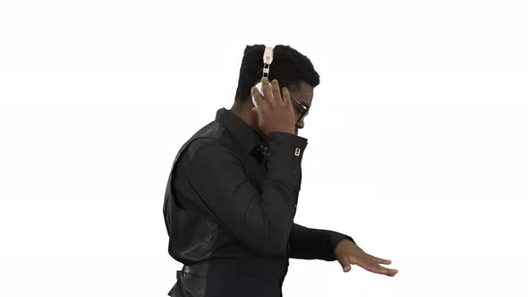 Young African American Man Listening To Music in Headphones and Grooving While Walking on White
