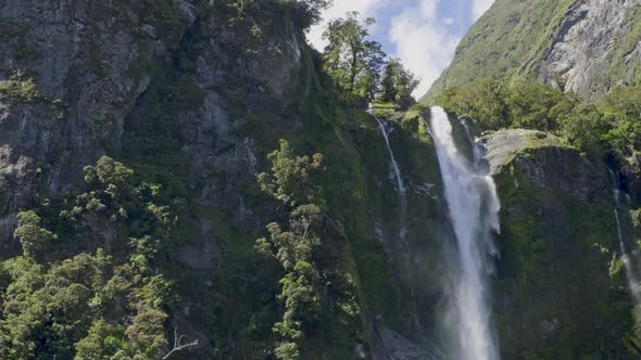 Stirling Falls Flowing Over A Steep, Mossy Cliff At Milford Sound In New Zealand. - wide shot