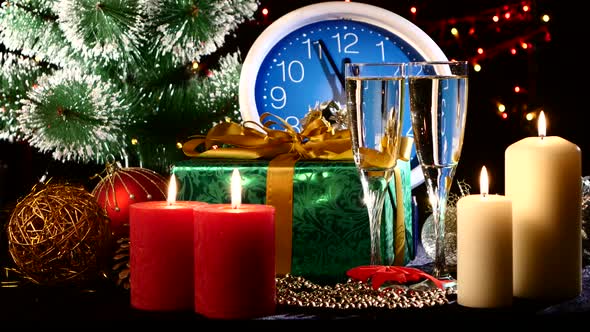 Glasses with Champagne on New Year Eve Against Wall Clock, Candles, Presents, Bokeh, Garland, on