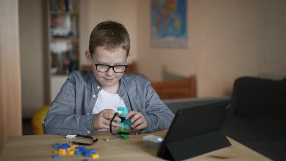 Happy Boy in Glasses Sits Connects Loop to Power Supply Programs on Tablet