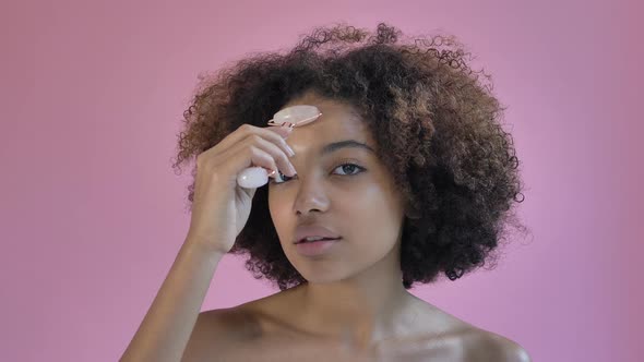 African American Model Massages Cheeks with Jade Roller