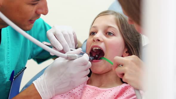 Dentist and assistant fixing teeth of cute girl, she's showing thumbs up