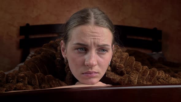 Young Girl is Sad Lying on a Bed Under a Blanket Closeup