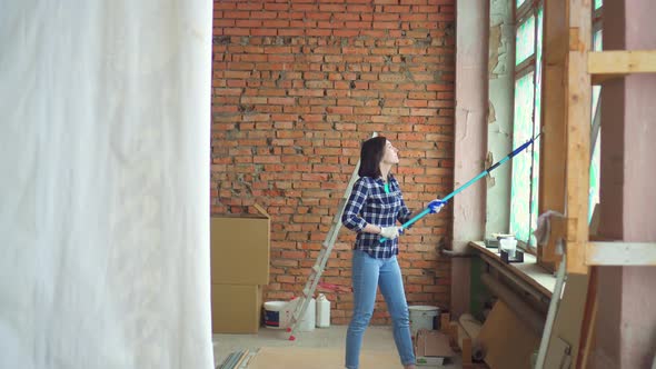 Portrait of a Beautiful Girl in a Plaid Shirt Makes Doityourself Repairs in the Apartment