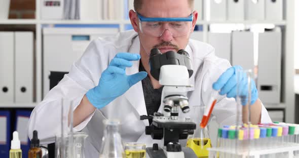 Scientist Chemist Wearing Glasses Holding Test Tube with Blood and Looking Microscope  Movie