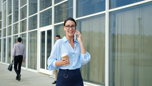 Independent Woman Talking on Cellphone Walking in City in Business District Smiling