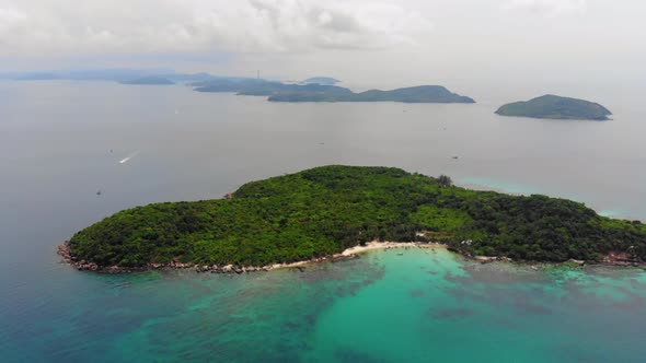 Aerial Panning View of Green Wild Tropical island Surrounded by Beautiful Turquoise Ocean, islands o