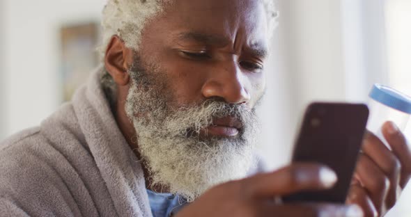 Senior man using smartphone while holding empty medication container