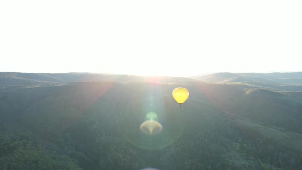 A Balloon Flies Over the Mountains in the Sunrise