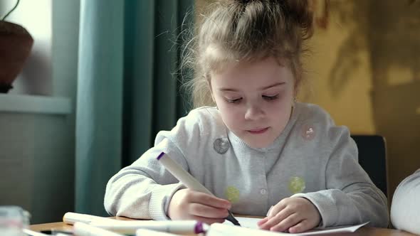 Little preschool girl enthusiastically draws with colored pencils creates art
