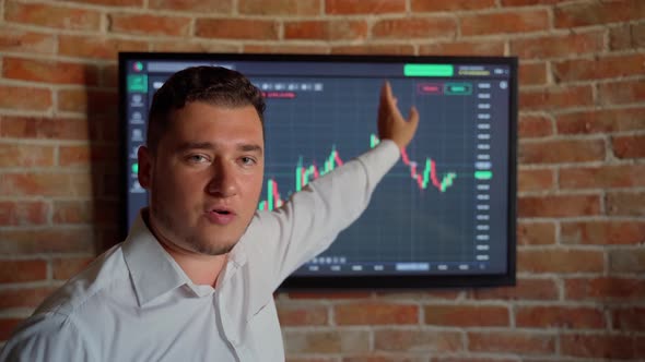 Man trader talking looking at camera graph money background indoors. Male person has video call