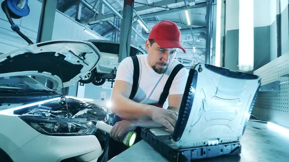 Car Repairman Uses His Laptop for a Vehicle Inspection